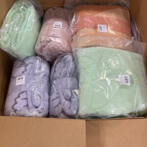 A stacked pallet of assorted new name-brand wholesale comforter pallets in various colors and styles