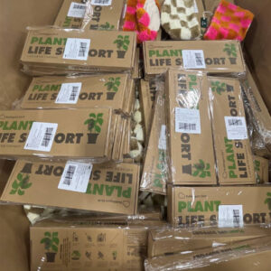 A pallet stacked high with a variety of new name-brand wholesale garden products, including watering cans, colorful planters, and gardening tools.