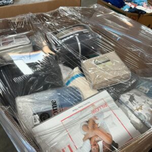 A neatly stacked pallet of diverse wholesale bed comforters and bedding liquidation items.