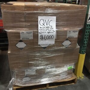 A diverse QVC liquidation pallet filled with electronics, home goods, and beauty products.